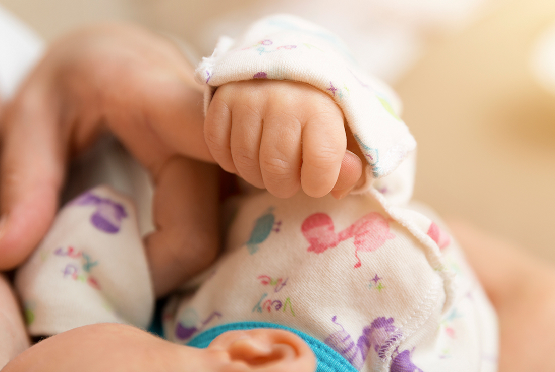 Baby hand gripping mother's finger