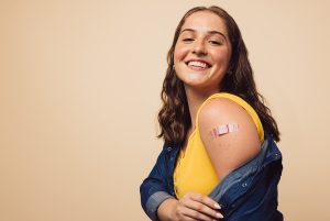 woman showing band-aid on upper arm indicating a flu shot