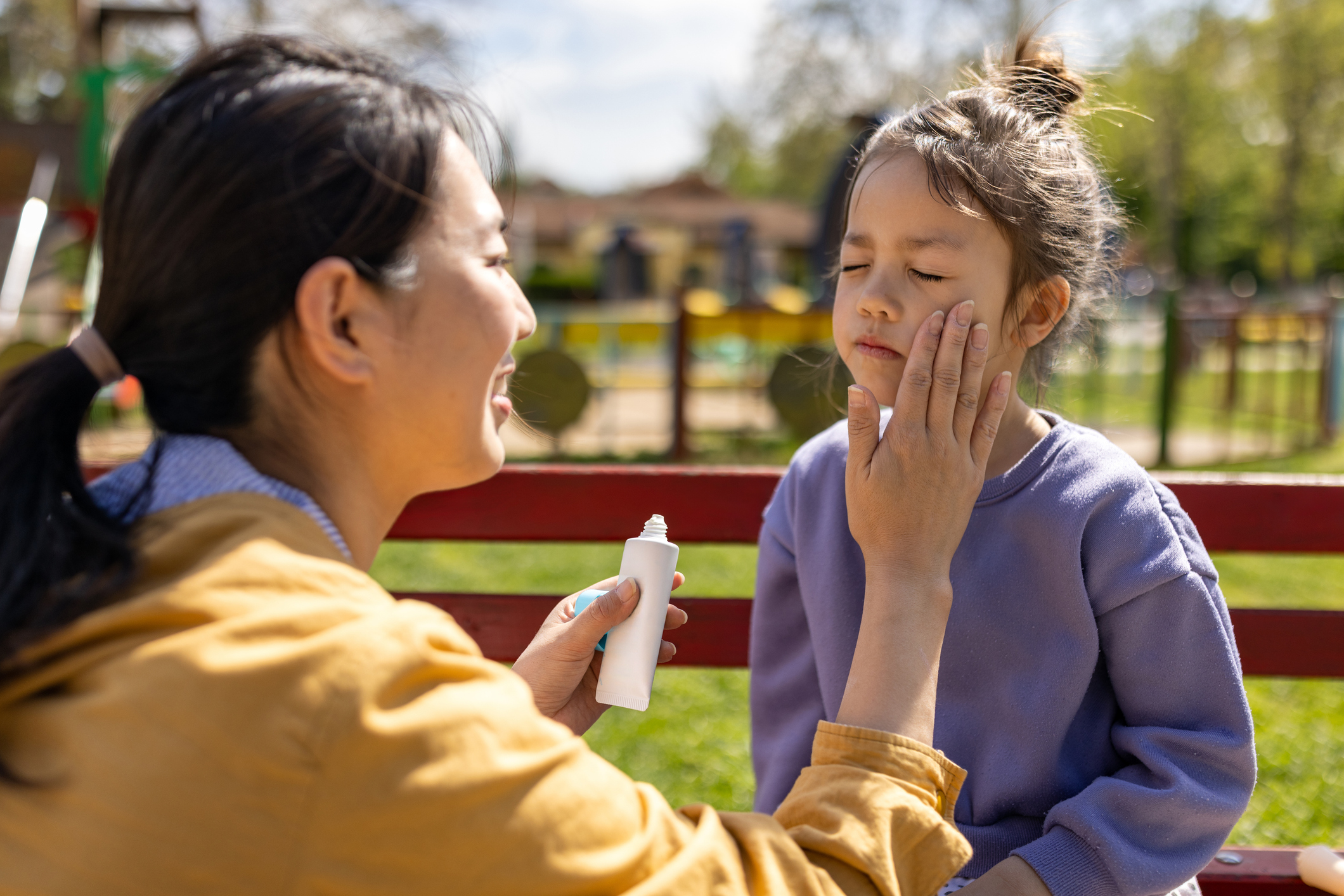 Mother applying sun-screen to her daughters face