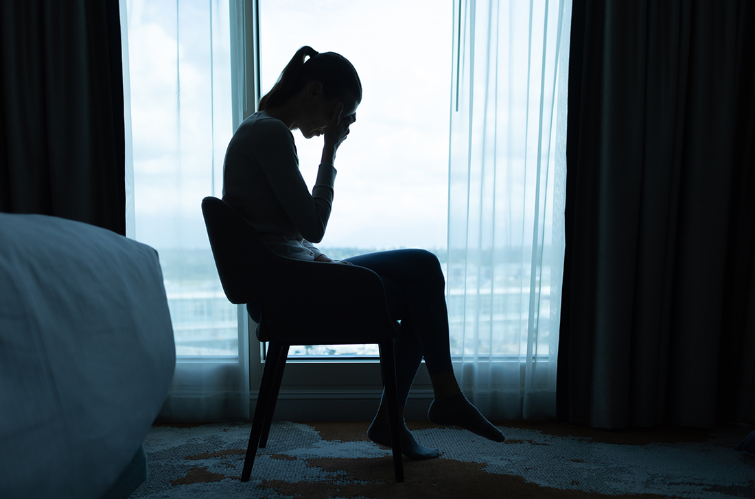 A woman sits in a chair holding her head in her hands